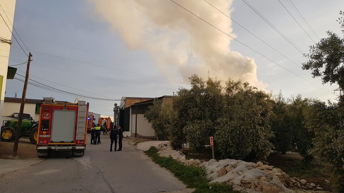 Una columna de humo se eleva desde la nave afectada por el incendio en la zona de las Peñuelas, en Lucena.