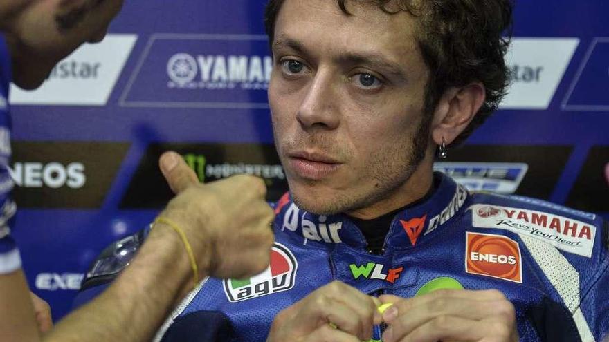 Valentino Rossi escucha las indicaciones de uno de sus asistentes en el box de Yamaha.