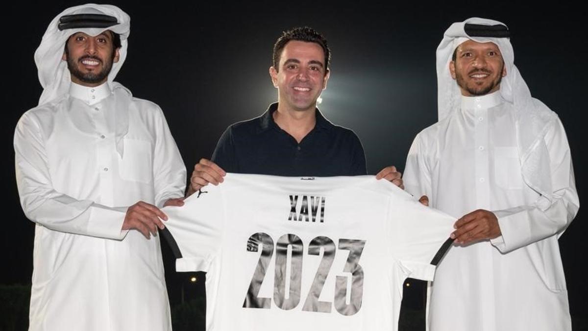 Xavi Hernández posa con dos dirigentes del Al Sadd con la camiseta ilustrativa del final de su contrato.