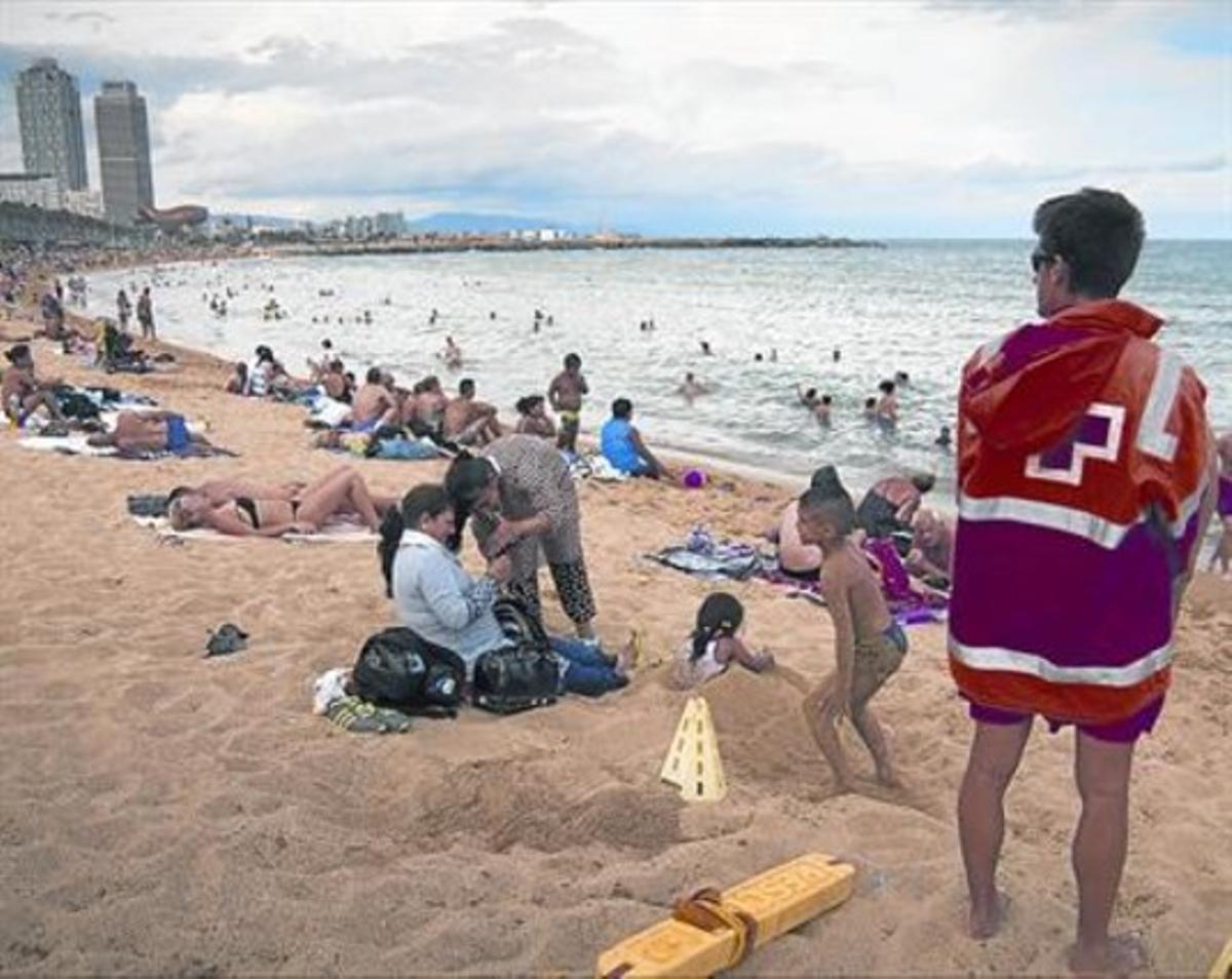 Un socorrista de la Creu Roja observa, divendres, la platja de la Barceloneta, sector del litoral barceloní en el qual la setmana passada es van atendre una desena de banyistes lesionats per meduses.