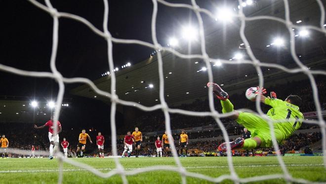 Paul Pogba (I) del Manchester United dispara un penalty que es parado por el portero Rui Patricio del Wolverhampton Wanderers durante el partido de la Premier League inglesa entre el Wolverhampton Wanderers y el Manchester United held en el Molineux