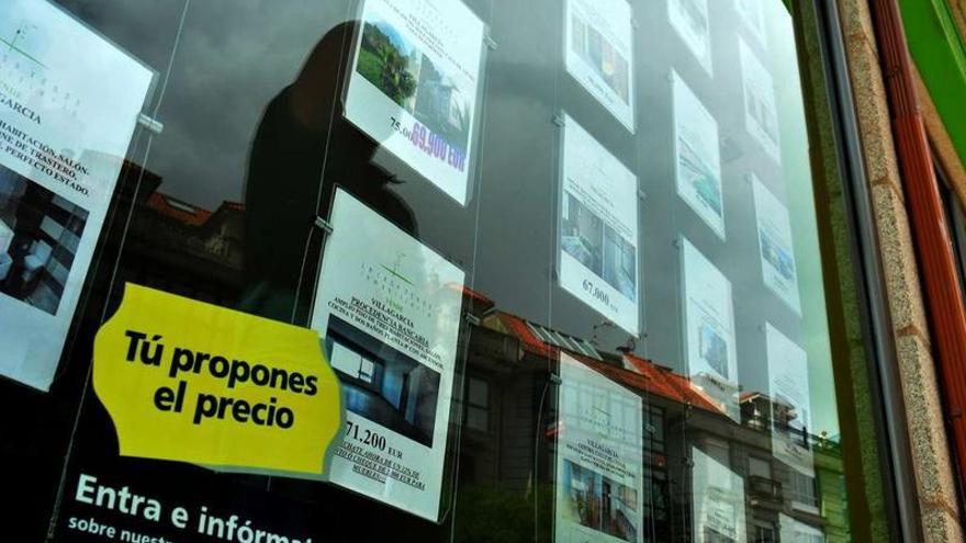 Multitud de ofertas de venta de viviendas en el escaparate de una agencia inmobiliaria de Vilagarcía.