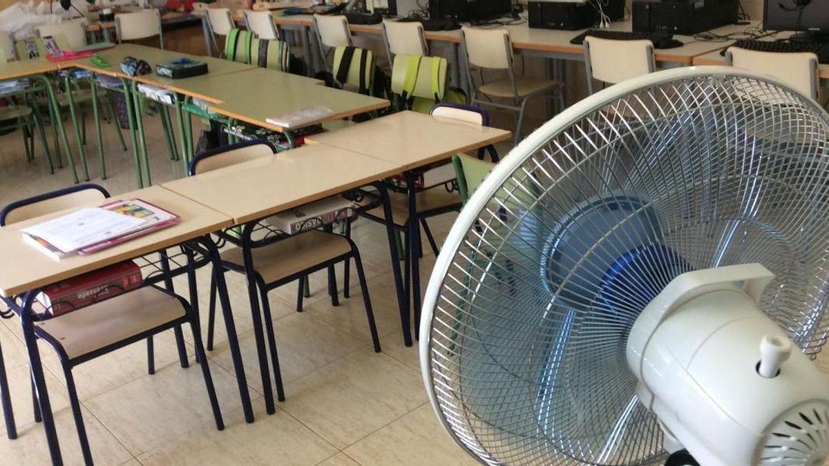 Imatge d'una aula d'un centre educatiu amb un ventilador per a pal·liar les altes temperatures.
