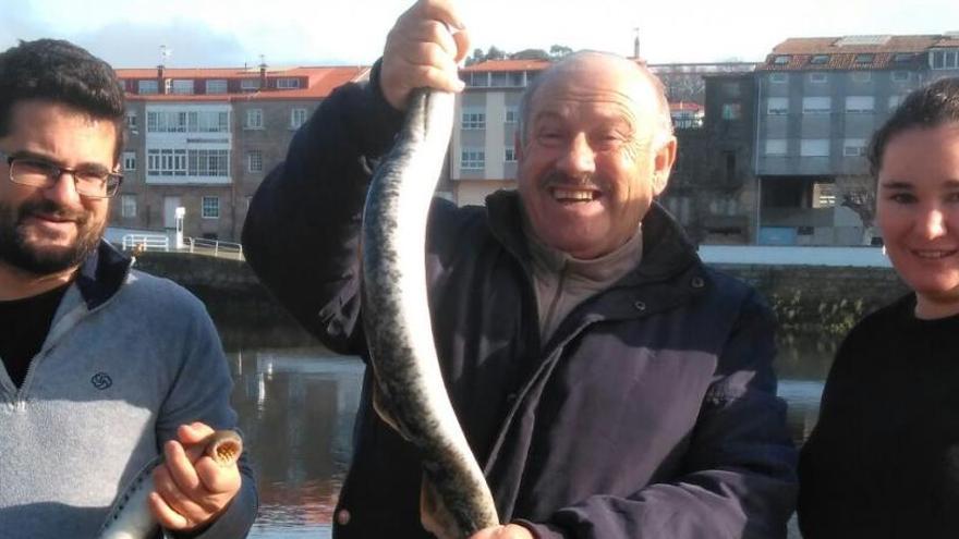 Ramón Agrasar y su esposa posan con las lampreas junto al hostelero Ángel Rodríguez (centro).