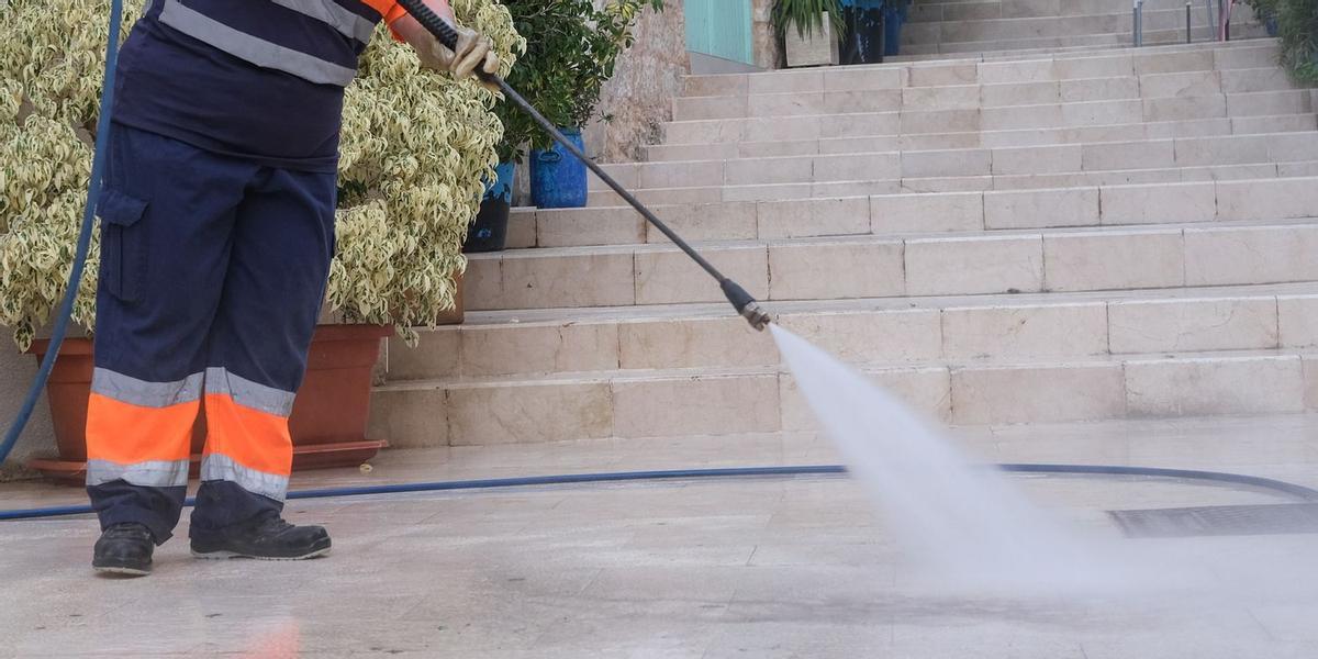 Imagen de archivo de una operaria realizando un baldeo para profundizar en la limpieza de una calle.