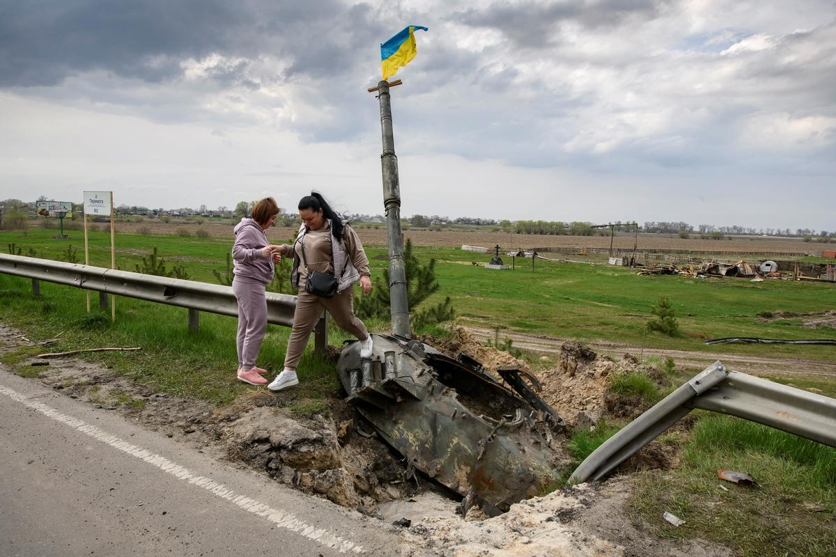 La gente junto a los escombros de la maquinaria militar rusa destruida durante la invasión rusa de Ucrania, en el pueblo de Rusaniv, en  Kiev