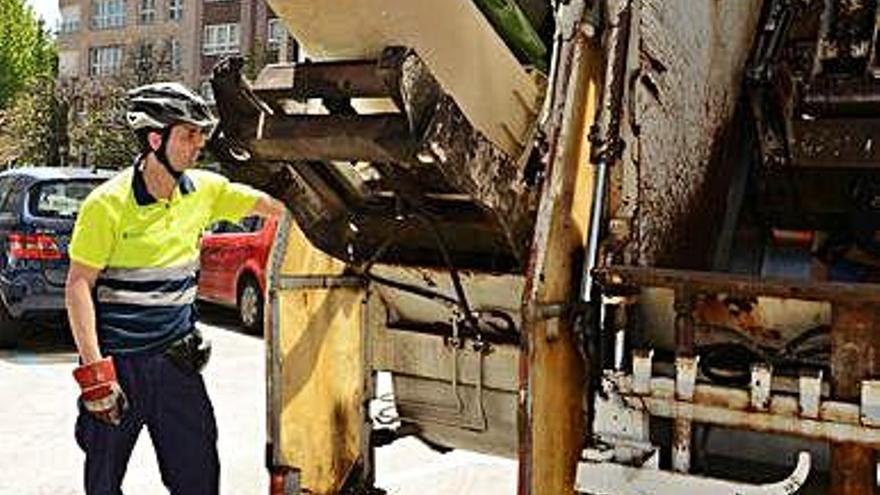 Un operario de la recogida de la basura vacía contenedores.