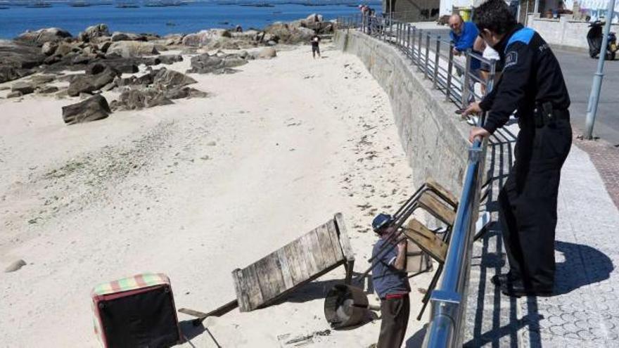 Un agente de policía y vecinos observan los muebles lanzados a la playa de Virxe das Mareas, ayer.  // Muñiz
