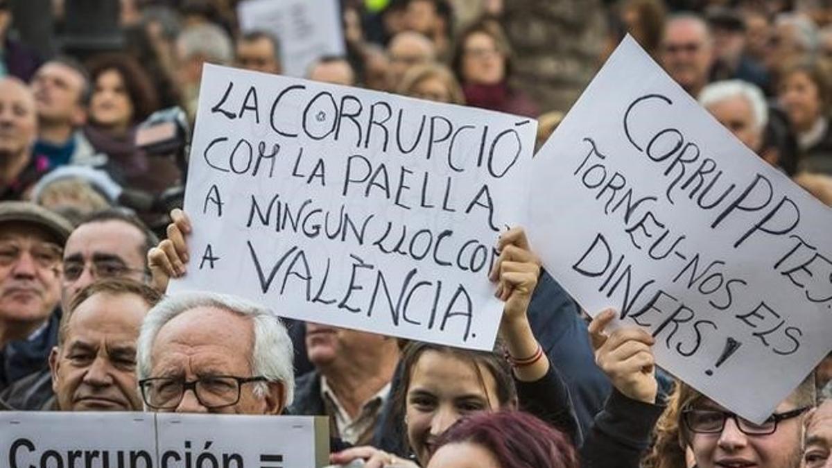 Asistentes a la manifestación contra la corrupción celebrada este domingo en Valencia portan carteles contra el PP y los casos que han afectado a esta comunidad.