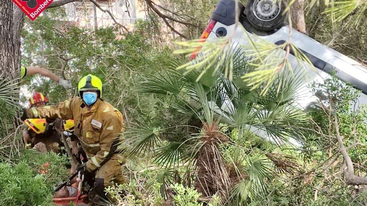 La furgoneta volcada y, a la izquierda, los bomberos sacando en camilla al conductor.