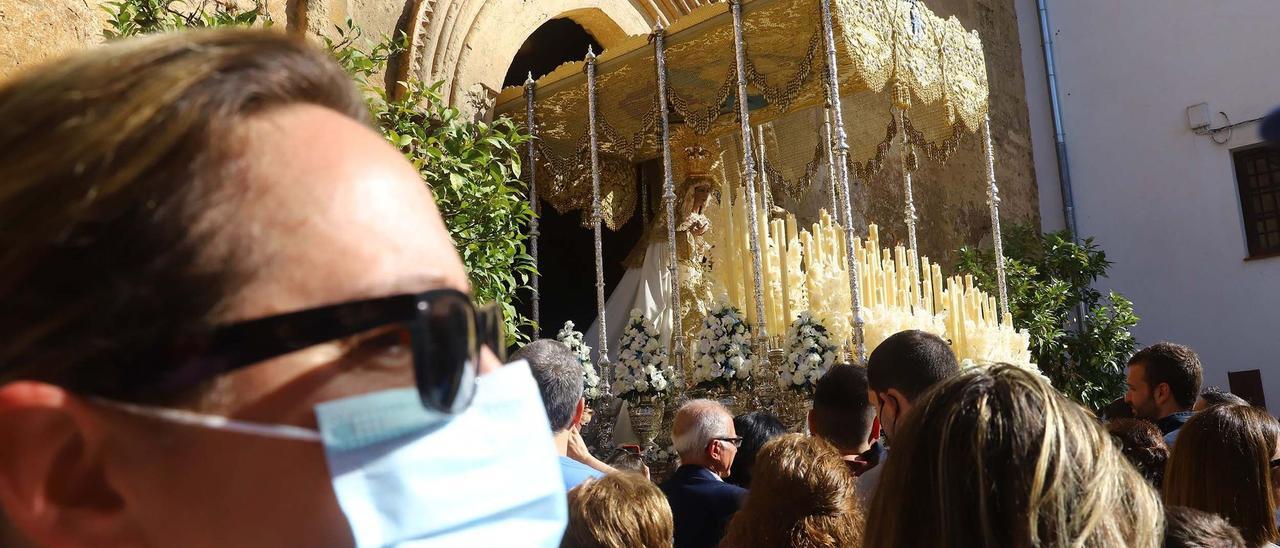 Una mujer con mascarilla, y numeroso público, durante la salida de una procesión en Córdoba.