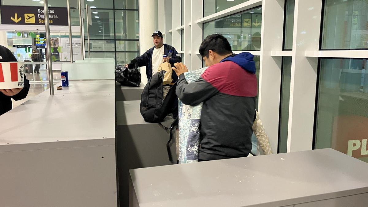 Juan y Jaïr, dos hombres sin hogar, recogen sus pertinencias al ser advertidos de abandonar la terminal donde durmen desde hace un mes.