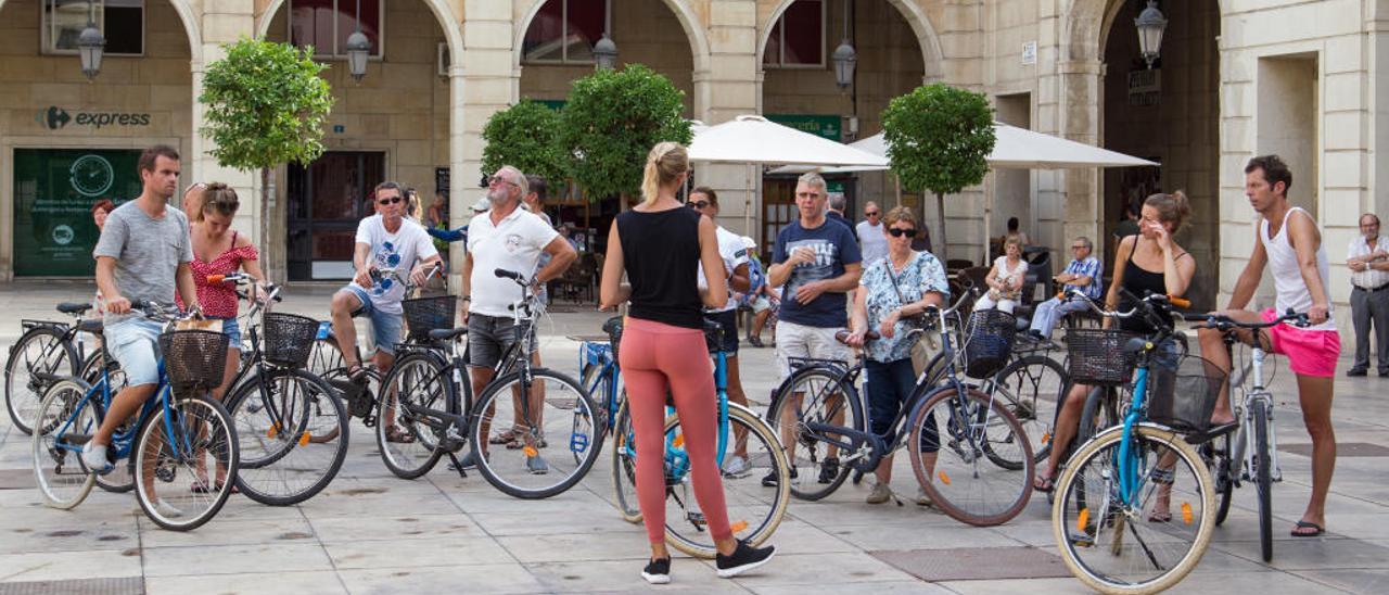 Un grupo de turistas recibe explicaciones de su guía en la plaza del Ayuntamiento de Alicante.