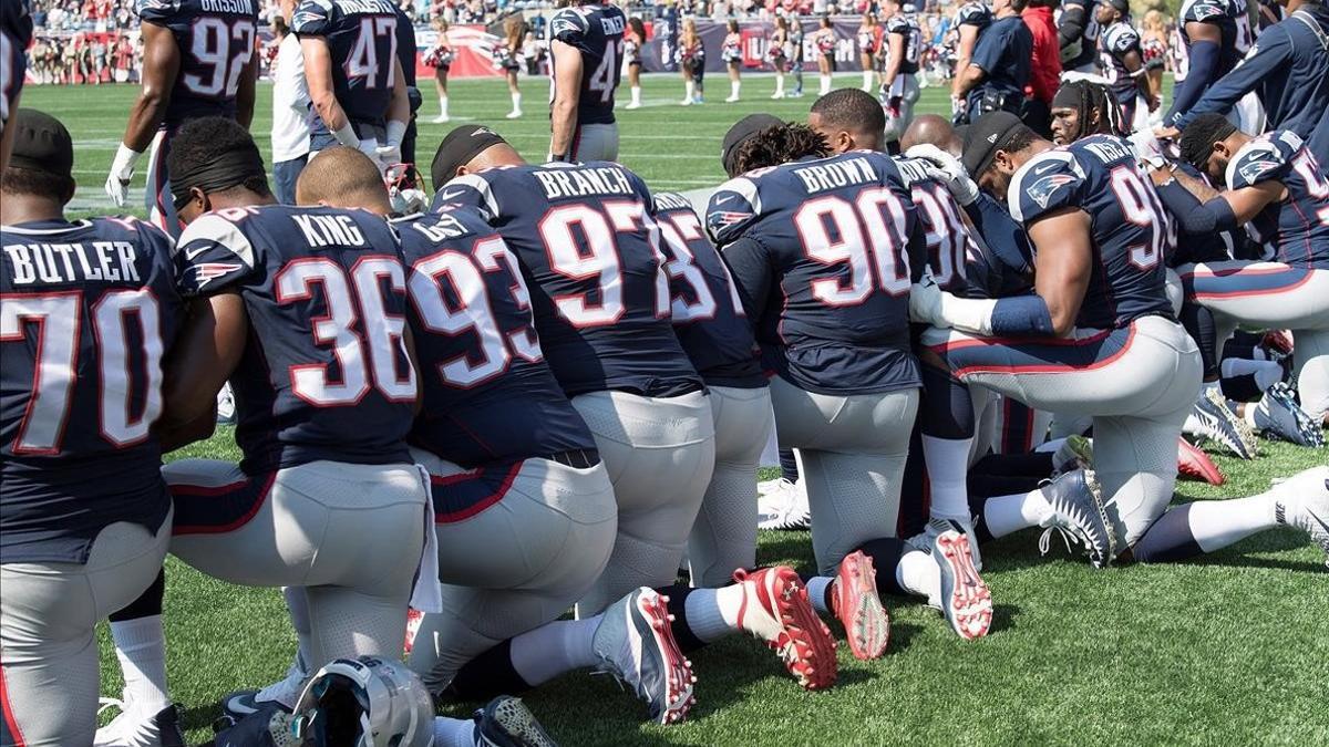 Los jugadores de New England Patriots protestan arrodillados durante el himno.