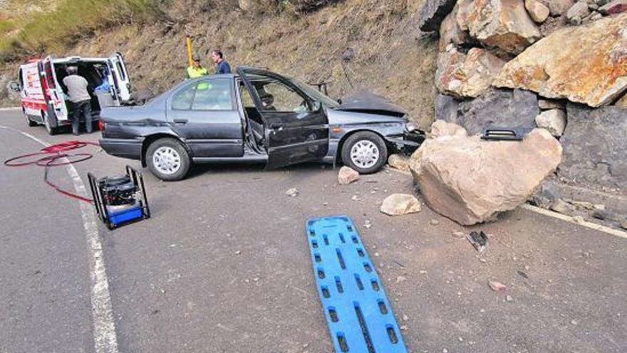 El vehículo accidentado y, al fondo, la ambulancia con el herido en su interior.