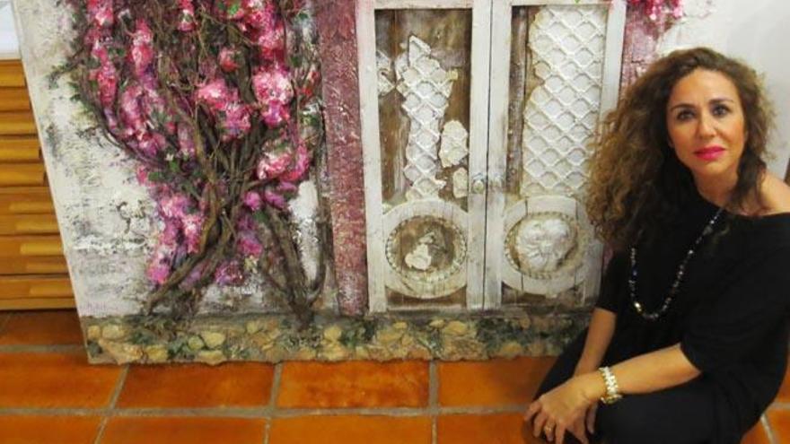 Marta Torres junto a un cuadro de una ventana ibicenca con una buganvilla.