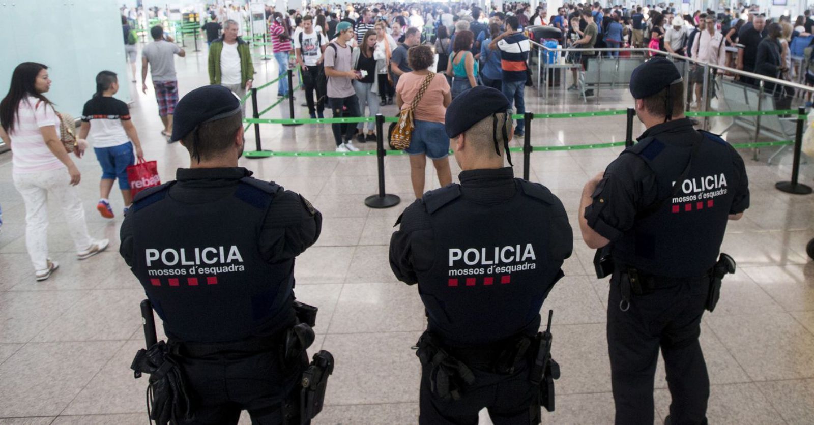 Tres agents dels Mossos vigilen la zona d’embarcament a l’aeroport del Prat. | QUIQUE GARCÍA / EFE
