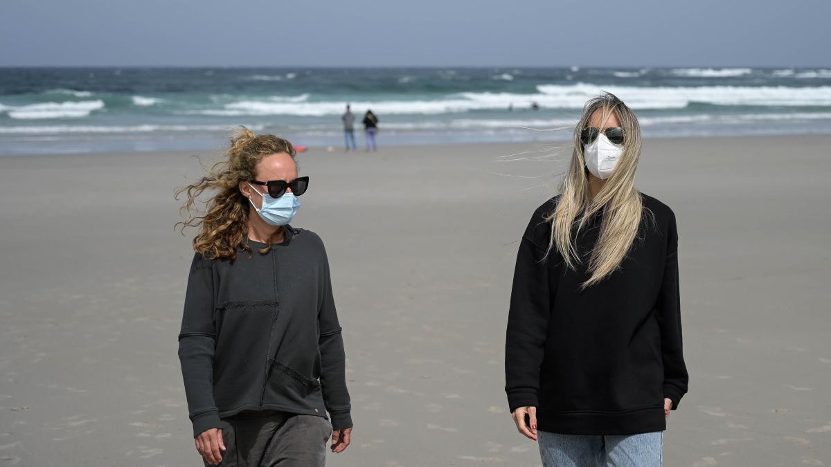 Dos mujeres con mascarilla en la playa.