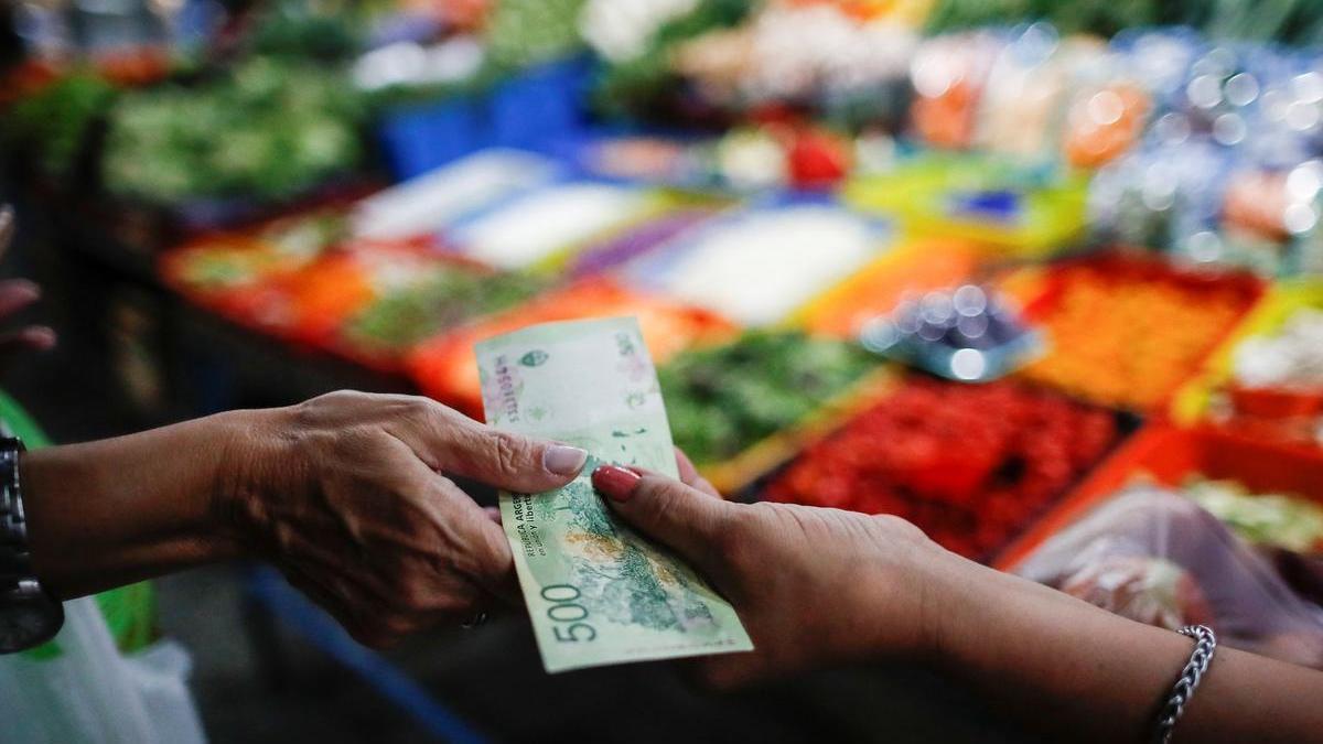 Una compradora paga en una tienda de frutas y verduras en un mercado de Buenos Aires.