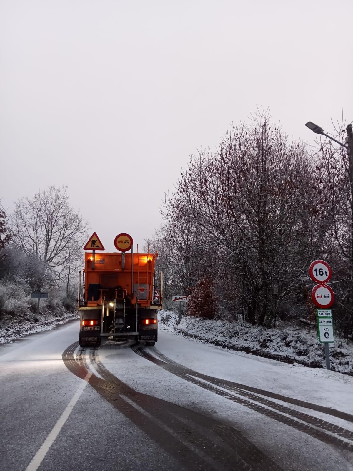 Una máquina quitanieve esparce fundentes en una de las carreteras teñidas de blanco.