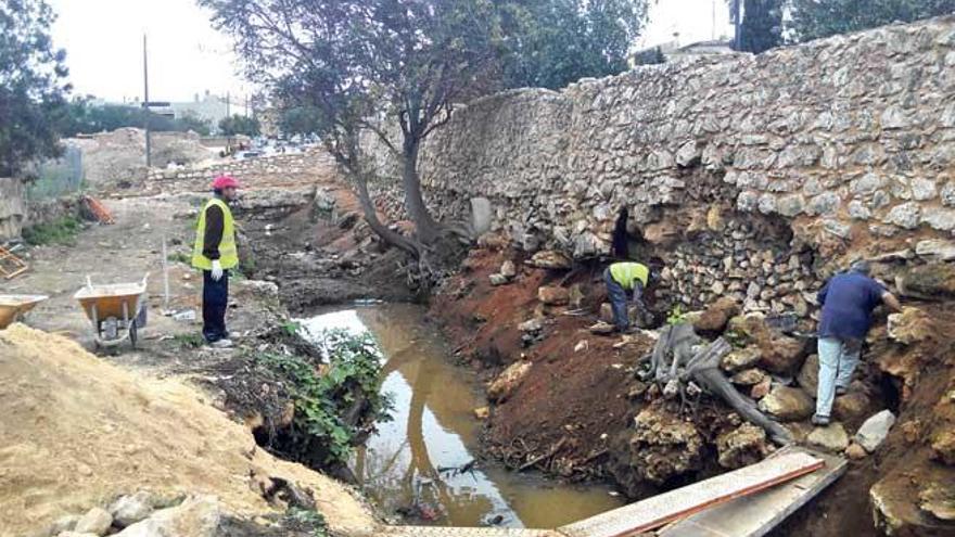 Operarios trabajando en la restauración de los muros bajo los que se abre uno de los fosos.