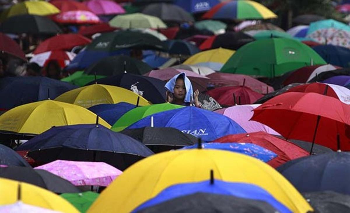 Una nena filipina, envoltada de paraigües de colors, es dirigeix a les espatlles del seu pare al Cementiri del Nord de Manila (Filipines) durant el Dia de Tots Sants.
