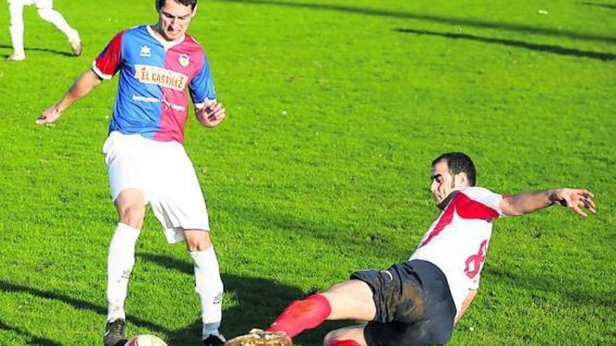 El jugador del Langreo Diego Arias controla el balón ante la entrada de Abraham, del Candás.