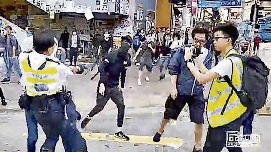 Un policía apunta con su arma a un manifestante en Hong Kong. // R.