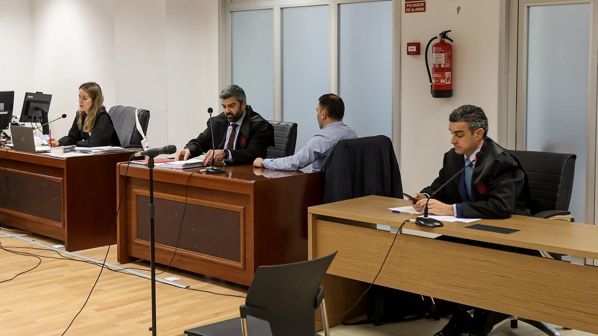 El policía declarado culpable, de espaldas entre sus dos abogados en la Audiencia de Alicante.