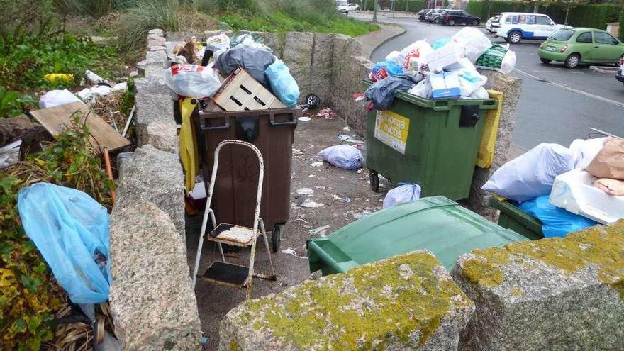 Basura esparcida alrededor de los contenedores, al lado de un supermercado en la N-VI en Perillo.