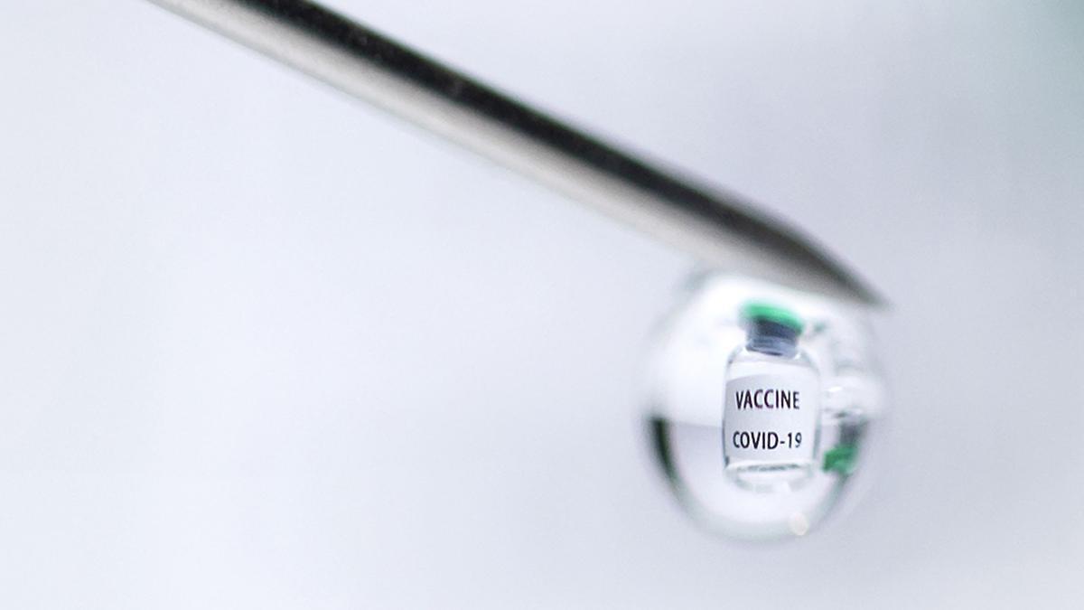 This photograph taken on December 7, 2021, shows a syringe with bottles reading &quot;Vaccine Covid-19&quot; in Paris. (Photo by JOEL SAGET / AFP)