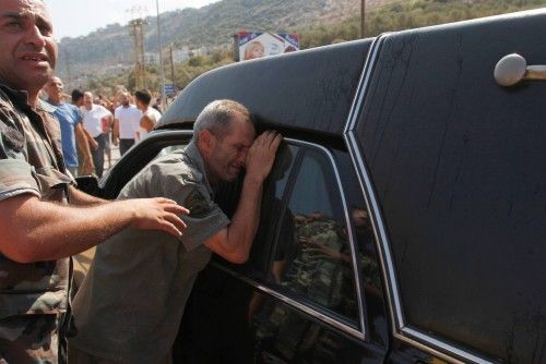 A father of a Lebanese soldier captured by hardline Syrian Islamists, reacts next to a hearse carrying the coffin of another soldier, during his funeral in Qalamoun, in Akkar