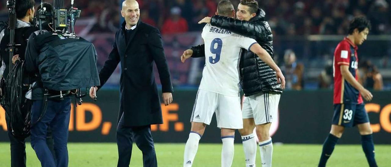 Zidane, a la izquierda, observa el abrazo de Benzema y Cristiano Ronaldo al final del partido.