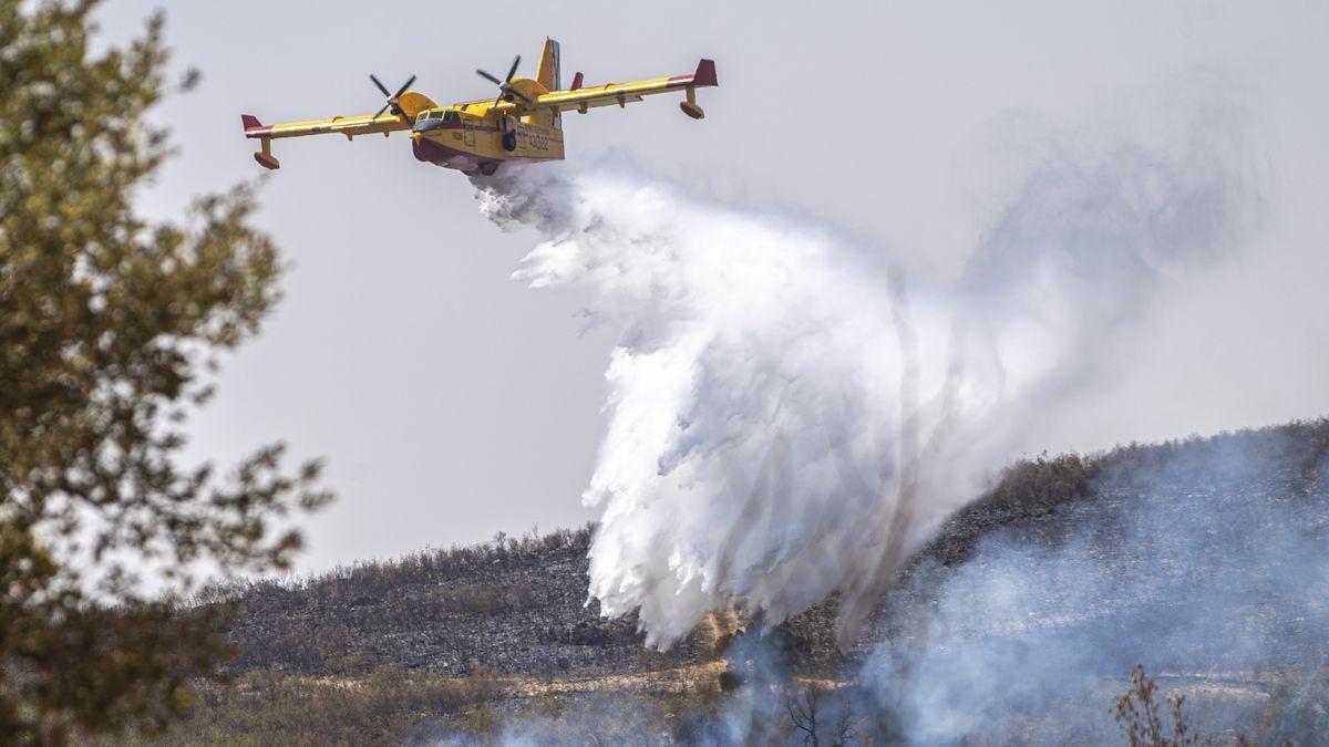 Un hidroavión descarga en la zona del incendio de Casas de Miravete, este domingo.