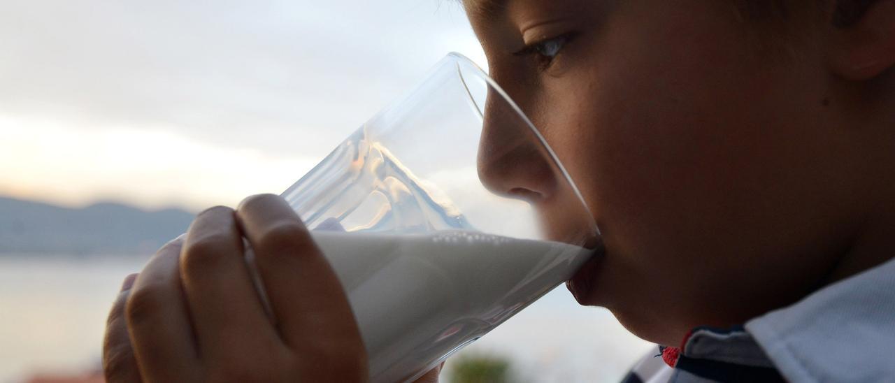 Un niño, bebiendo un vaso de leche.