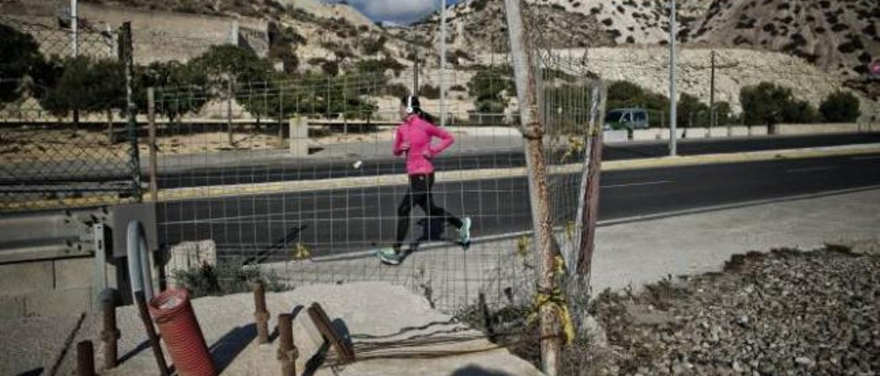 Una joven pasa corriendo junto a los restos del paseo que se inició junto a la carretera de la Cantera, hoy abandonado.