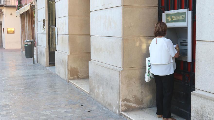 Una clienta saca dinero de una sucursal bancaria en Málaga.