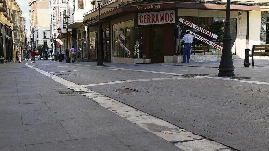 Vista del estado del pavimento de la calle y, al fondo, uno de sus comercios.