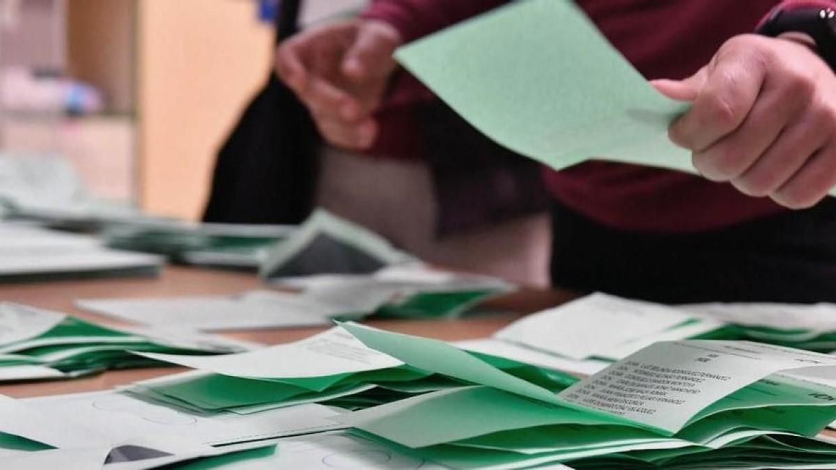 Una persona escoge papeleta en un colegio electoral.