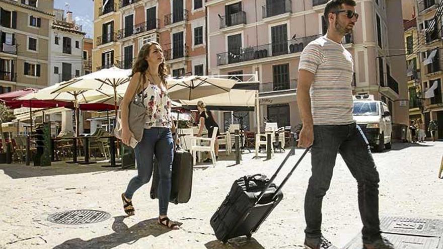 Una pareja de turistas transportan sus maletas por el centro de Palma.