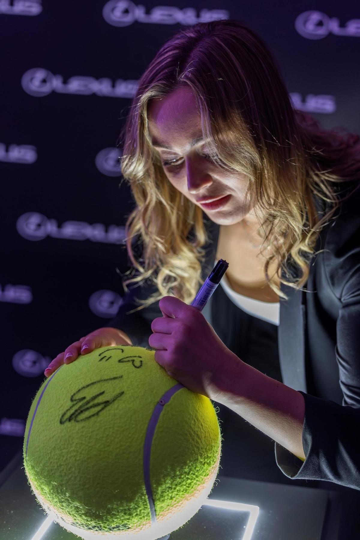 Badosa, firmando una pelota de tenis gigante.
