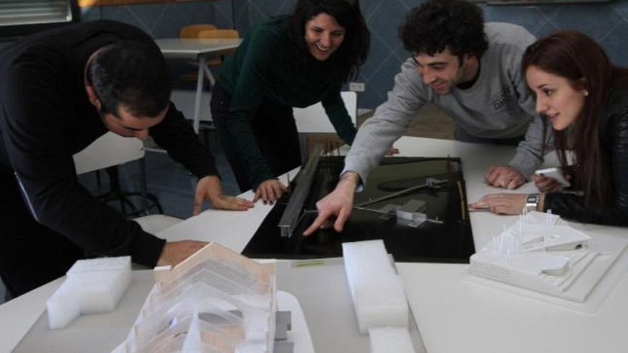 Desde la derecha, los alumnos Diana Rubio y Ángel Martín observan los detalles de sus proyectos fin de Grado con dos profesores de la Escuela.