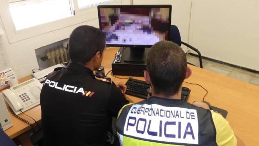 Dos agentes de la Policía Nacional observan las fotografías en la pantalla del ordenador.