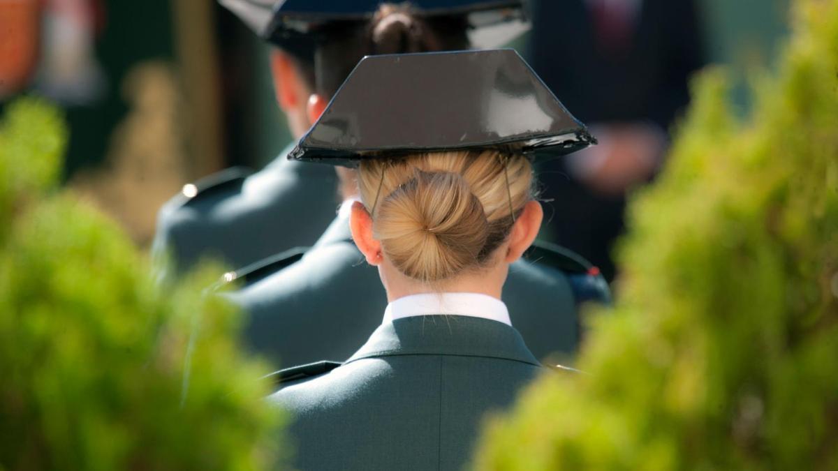 Una mujer, agente de la Guardia Civil, con el tricornio y el uniforme junto a compañeros.