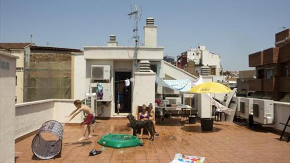 Regateando el calor 8 Una de las familias realojadas en el edificio de la Bordeta se refresca en la terraza, el pasado lunes.