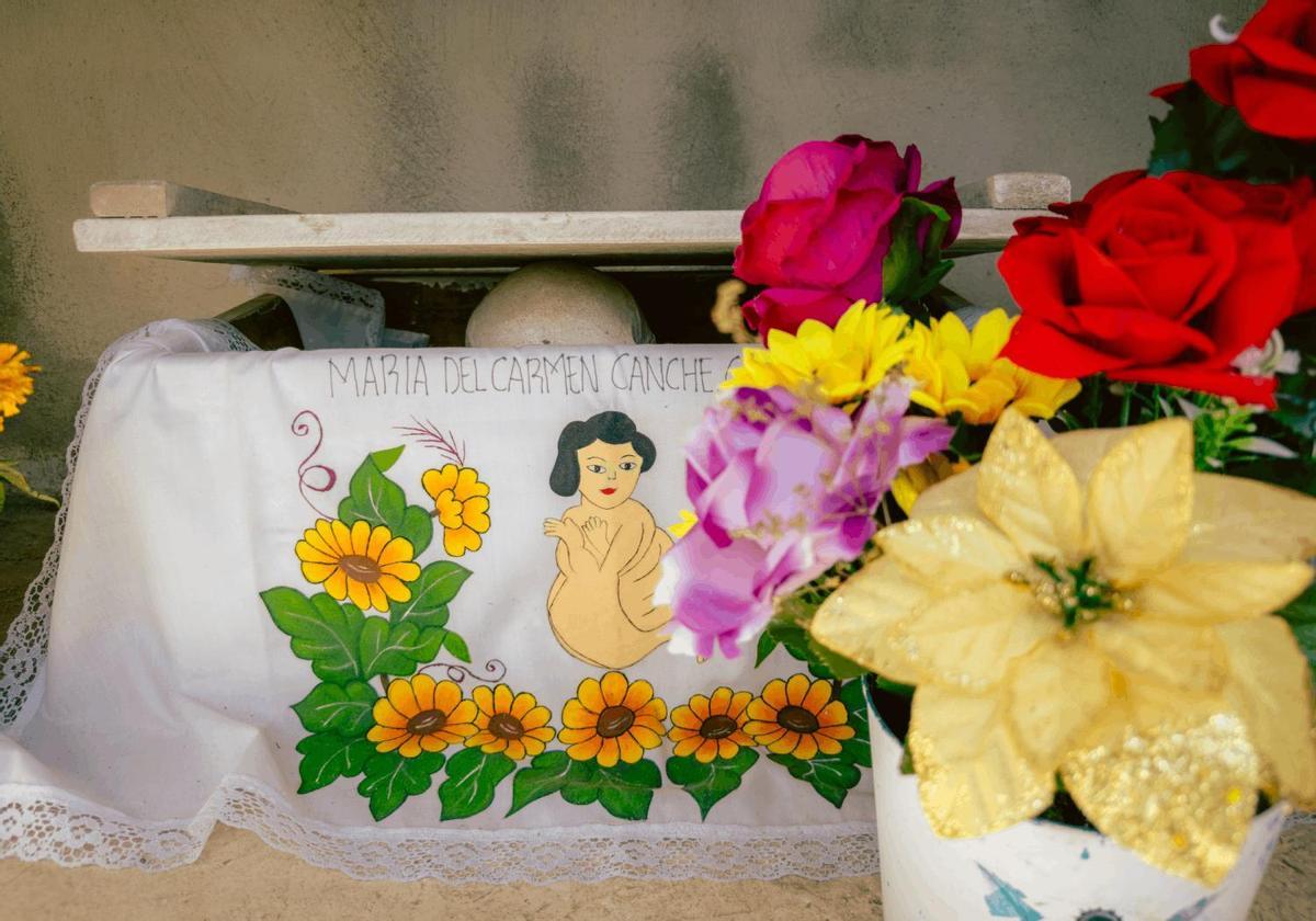 Pomuch, México. Una caja de huesos con el nombre de la difunta bordado en tela, rodeada de flores frescas, en el cementerio de Pomuch. Cada año, para el Día de Muertos, las familias de este pueblo de Campeche sacan los restos de sus seres queridos, los limpian con sus propias manos y los visten con manteles nuevos, en una de las tradiciones funerarias más singulares de México. (iPhone 14 Pro)