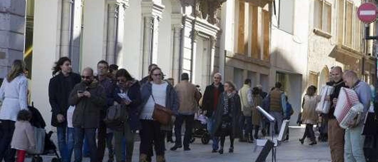 Músicos y peatones en la calle Cimadevilla.