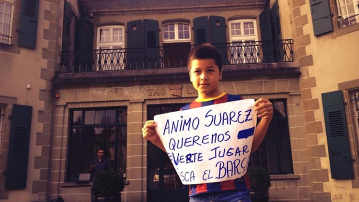 Un niño posa junto a una pancarta de apoyo a Suárez en la entrada de la sede del TAS