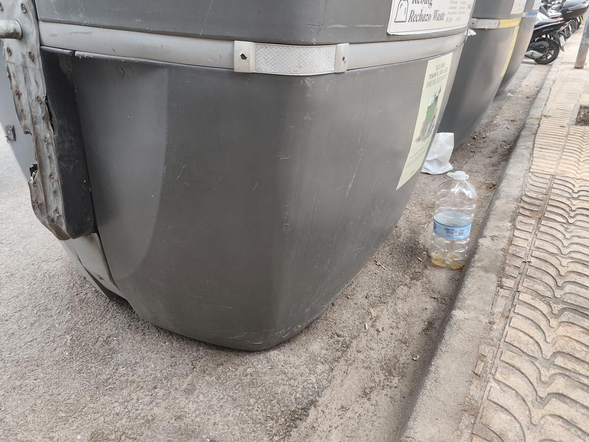Contenedores rodeados de suciedad y una garrafa con orina en ses Figueretes