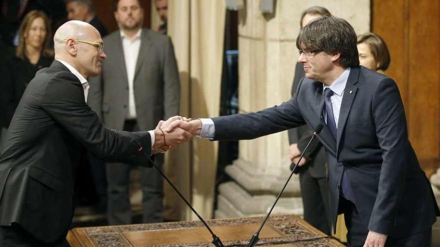 Carles Puigdemont, a la derecha, estrecha la mano de su consejero de Exteriores, Raül Romeva. // Efe